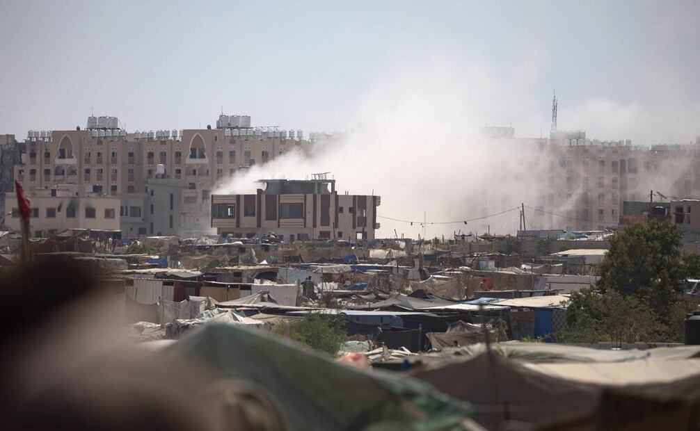 Una columna de humo se eleva mientras vehículos militares israelíes avanzan por un campamento de palestinos desplazados internos, en Jan Yunis. Foto: EFE