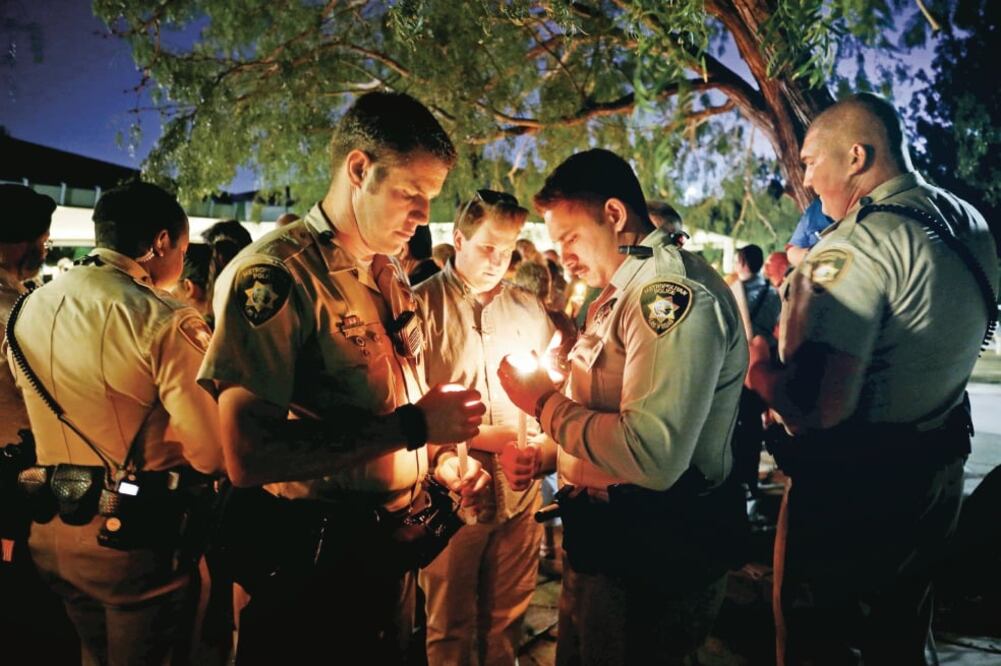 Policías sostienen velas durante una vigilia por las víctimas del tiroteo en el festival de música country Route 91, en Las Vegas (CHRIS WATTIE. REUTERS)