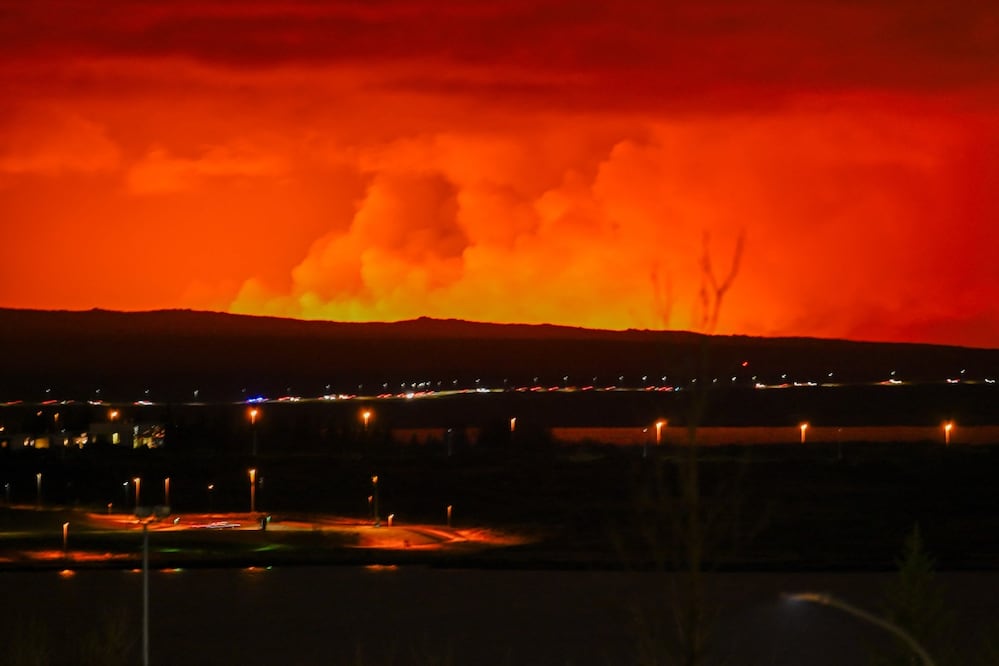 El cielo se tiñe de naranja mientras la lava  fluye desde una fisura en la península de Reykjanes al norte de la ciudad evacuada de Grindavik, en el oeste de Islandia. Foto: AFP
