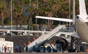 Los catorce pasajeros españoles que iban a bordo del crucero que ha sufrido un brote de hantavirus durante su travesía por el Atlántico Sur, el MV Hondius, han embarcado en el aeropuerto de Tenerife Sur en el avión del Ejército del Aire que los trasladará a Madrid, para iniciar un periodo de cuarentena en el Hospital Gómez Ulla. En la imagen, miembros de la Unidad Militar de Emergencias con trajes de protección en la escalerilla de la aeronave. Foto: EFE
