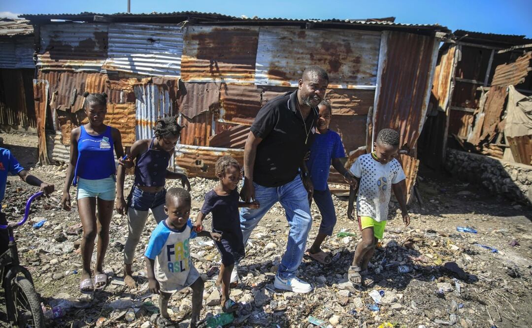 Jimmy Chérizier, un expolicía de élite conocido como Barbacue y que ahora dirige una federación de pandillas, camina de la mano de varios niños en una visita al distrito de La Saline en Puerto Príncipe, Haití. Foto: AP