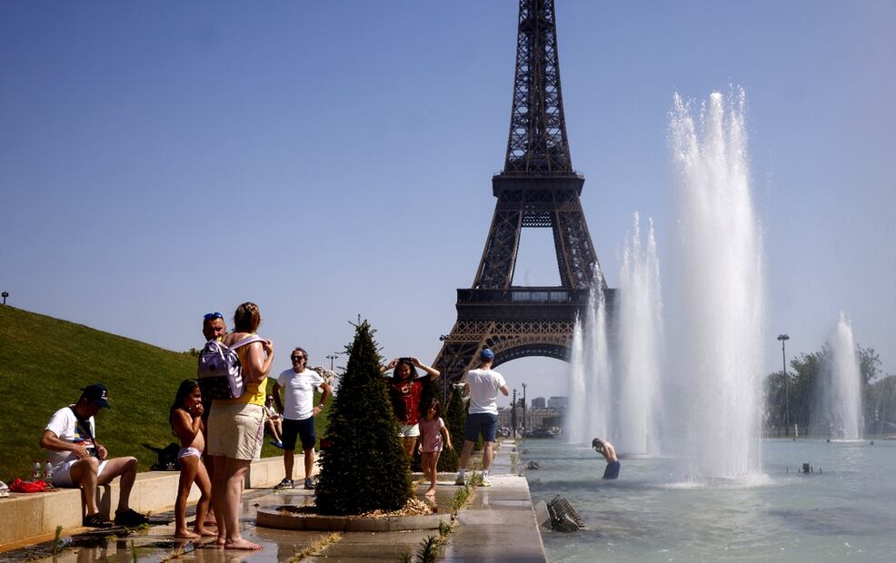 Varias personas se refrescan con agua de la fuente Varsovie, junto a la Torre Eiffel en París, Francia. Foto: EFE