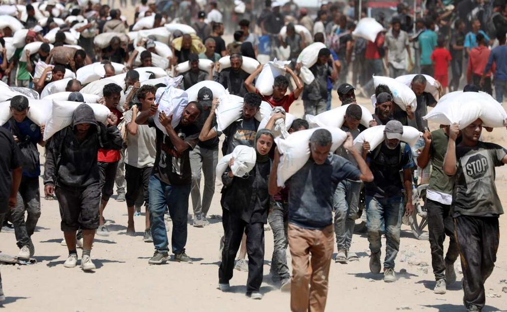 Imagen del 27 de julio de 2025 de palestinos cargando sacos de harina después de que la ayuda humanitaria entrara en Gaza a través de un paso fronterizo, en Beit Lahia, en el norte de la Franja de Gaza. El Ejército israelí anunció el domingo una pausa humanitaria diaria de 10 horas en sus operaciones en partes de la Franja de Gaza, junto con la apertura de rutas seguras para la entrega de ayuda, en medio de la creciente presión internacional por la agravación de la crisis alimentaria allí. Foto: Xinhua