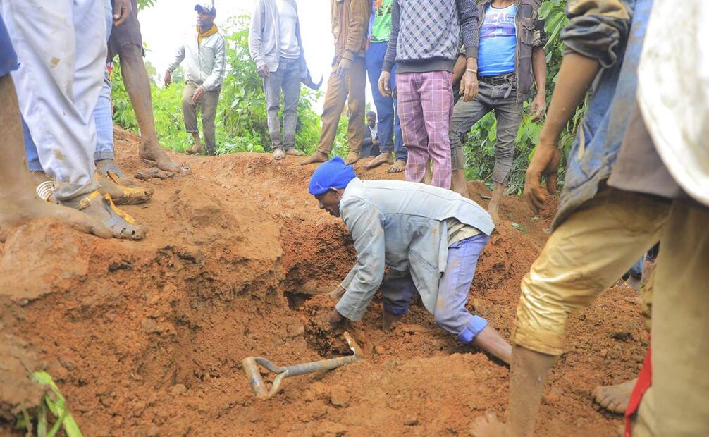 Hombre busca sobrevivientes mientras cientos de personas se congregan en el lugar donde se produjo un deslave. Foto: AP