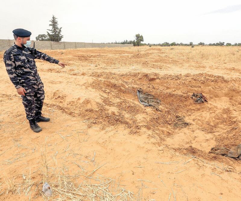 Un agente de las fuerzas de seguridad afiliadas al Ministerio del Interior del GNA, en una fosa común a 65 kilómetros de Trípoli, el 11 de junio. Foto: Mahmud TURKIA. AFP
