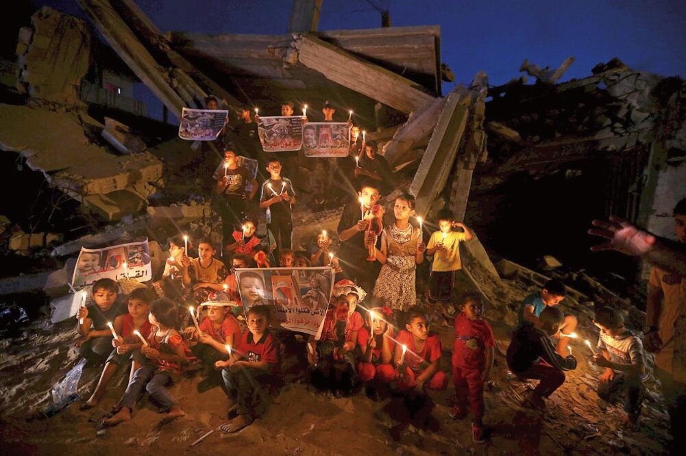 Niños palestinos con velas en una vigilia ayer en Rafah, en la Franja de Gaza, para recordar al bebé Ali Dawabsha, de 18 meses, quien murió quemado vivo cuan do presuntos ultraderechistas judíos incendiaron su casa en Duma (IBRAHEEM ABU MUSTAFA. REUTERS)