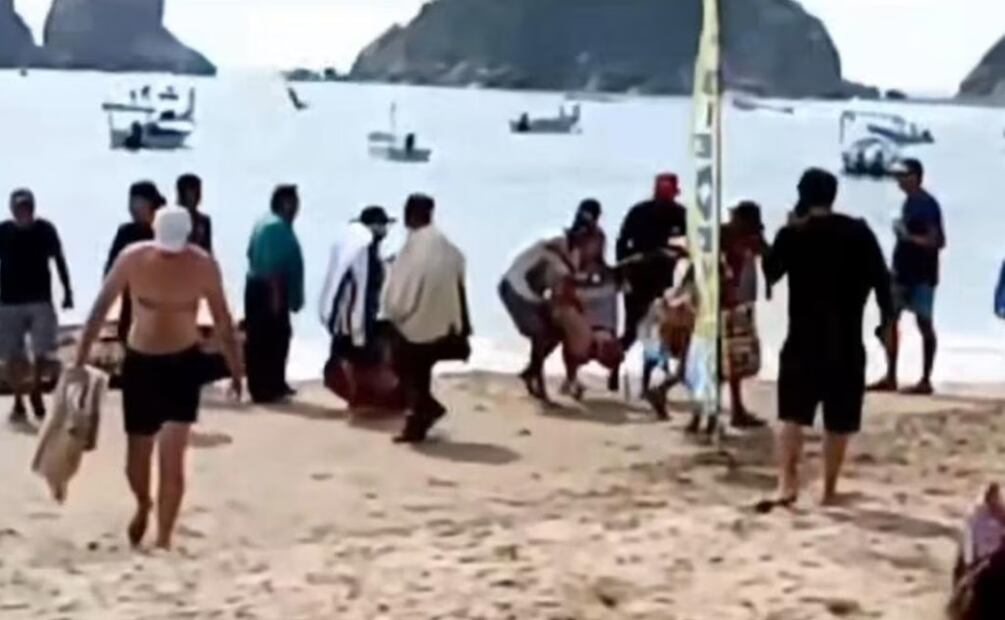 Momento exacto en que sacan a la mujer atacada por el tiburón. Foto: Especial