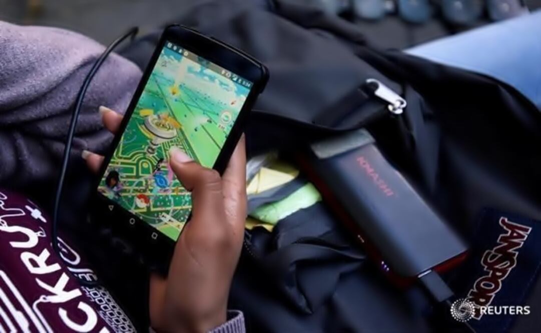 A woman uses a portable battery pack to charge her phone while playing "Pokemon Go". (Photo: Reuters)