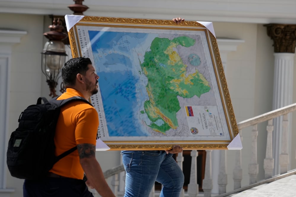 Un hombre lleva el "nuevo mapa de Venezuela" con el territorio del Esequibo, una gran franja de tierra administrada y controlada por Guyana pero reclamada por Venezuela, al edificio de la Asamblea Nacional en Caracas, Venezuela. Foto: AP