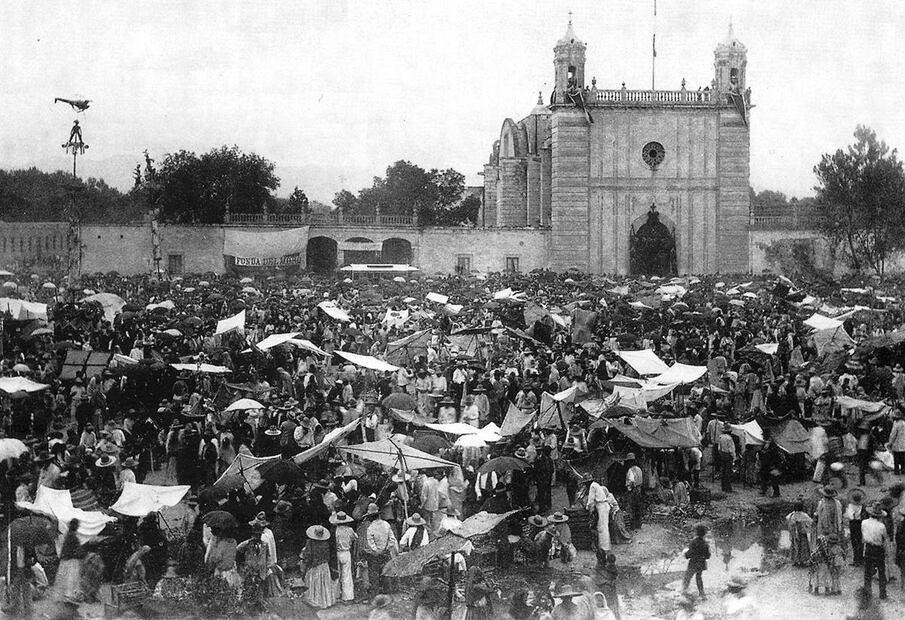 La plaza y el templo de Nuestra Señora de los Ángeles, en la colonia Guerrero, alrededor de 1880. Se aprecia que la iglesia aún no era modificada ni se le había agregado la cúpula; a los lados está el panteón, hoy desaparecido, y sobre la explanada hay diversos puestos en los días cercanos a la fiesta patronal.
Imagen: "Guía retrospectiva de la Ciudad de México".