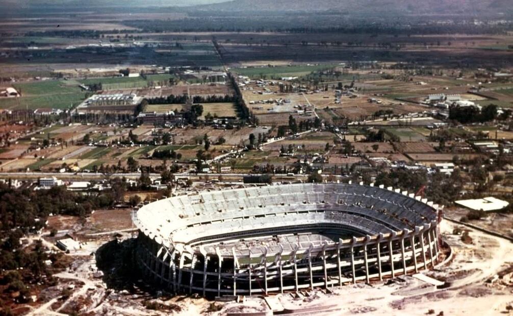 El Estadio Azteca en construcción y su entorno cerca de 1964, donde resaltan el cemento y el acero tal cual. Este espacio, obra de Pedro Ramírez Vázquez y Rafael Mijares, se inauguró en 1966; justo detrás está la Calzada de Tlalpan, al fondo se ven los volcanes Iztaccíhuatl y Popocatépetl. Colección Carlos Villasana.