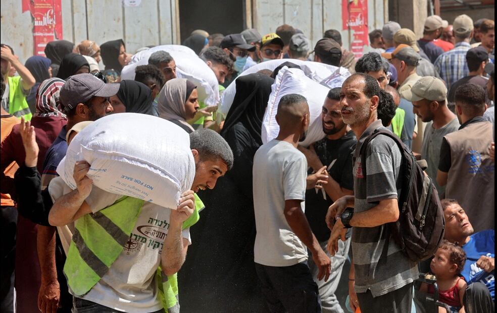 Palestinos llevan bolsas de ayuda de un almacén del Programa Mundial de Alimentos (PMA) de la ONU en la calle Al-Jalaa de la ciudad de Gaza, el 12 de julio de 2025. Foto: AFP