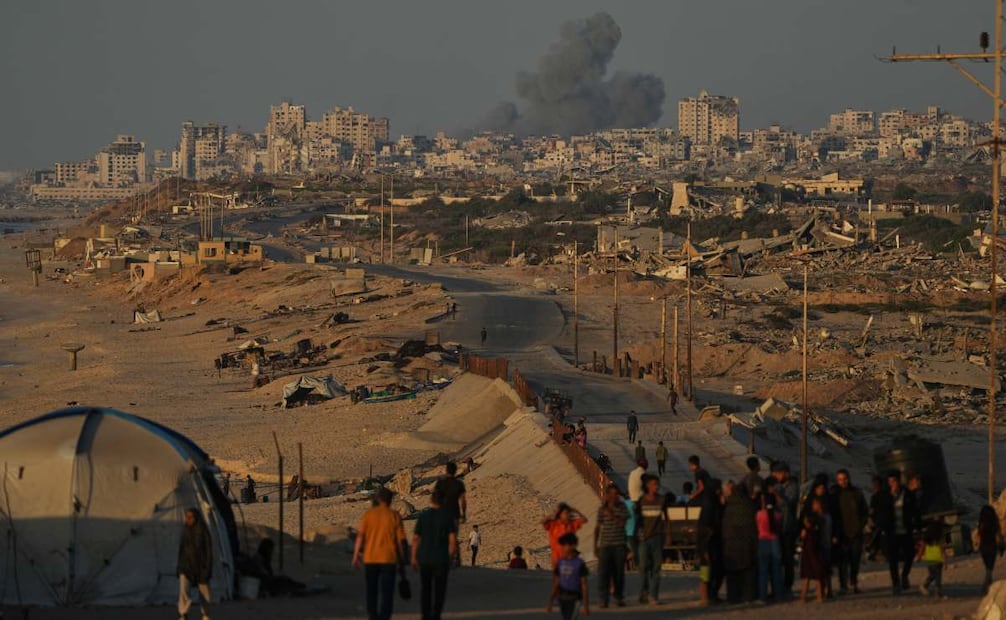 Palestinos desplazados caminan por la carretera costera, con el humo que se eleva hacia el cielo tras un ataque militar israelí en la ciudad de Gaza, visto desde el centro de la Franja de Gaza, el miércoles 8 de octubre de 2025. Foto: AP