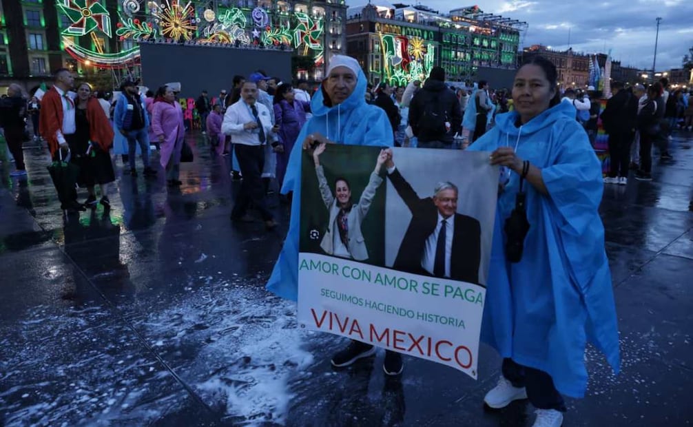 Mientras oscurece rumbo al primer Grito de Sheinbaum, asistentes cargan pancartas con la fotografía del expresidente Andrés Manuel López Obrador con la consigna "amor con amor se paga". Foto: Fernanda Rojas/ EL UNIVERSAL
