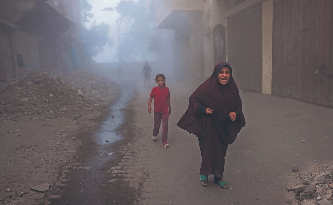 Una palestina y sus hijos huyen de los ataques aéreos israelíes contra un edificio al oeste de Jabalia, en el norte de la Franja de Gaza. Foto: de BASHAR TALEB. AFP