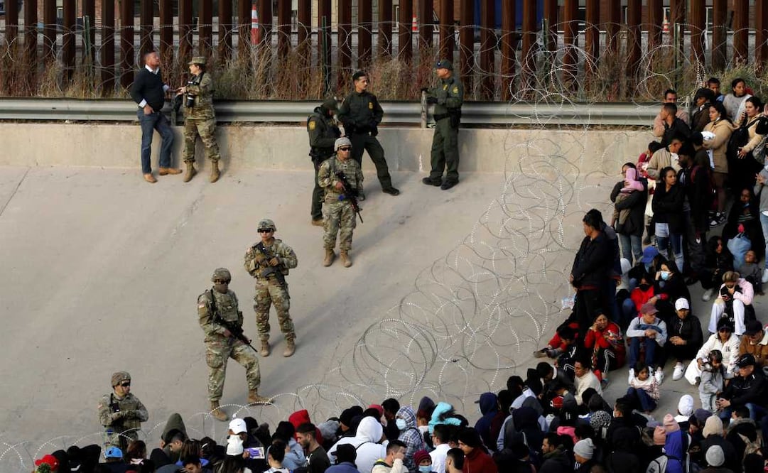 Migrantes se congregan a orillas del Río Grande en la frontera de Estados Unidos con México el 20 de diciembre de 2022, donde miembros de la Guardia Nacional de Texas acordonan un espacio en el muro fronterizo de Estados Unidos. Foto: AP