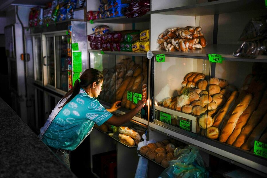 Un trabajador de una panadería ajusta la tienda durante un apagón en Caracas. Foto: AP