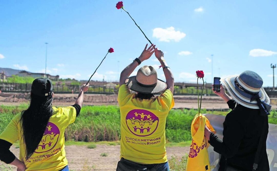 Mujeres saludan con flores rojas durante la protesta binacional Madres de la Frontera: Amor sin fronteras, en contra de las políticas fronterizas estadounidenses, en el marco de la celebración del Día de las Madres, a orillas del río Bravo en Ciudad Juárez, Chihuahua. Foto: AFP