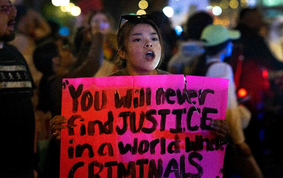 Una manifestante sostiene un cartel con con la leyenda "Nunca encontrarás justicia en un mundo donde los criminales hacen las reglas", durante una protesta contra las redadas migrantes en Chicago, Illinois, el 10 de junio de 2025. Foto: AFP