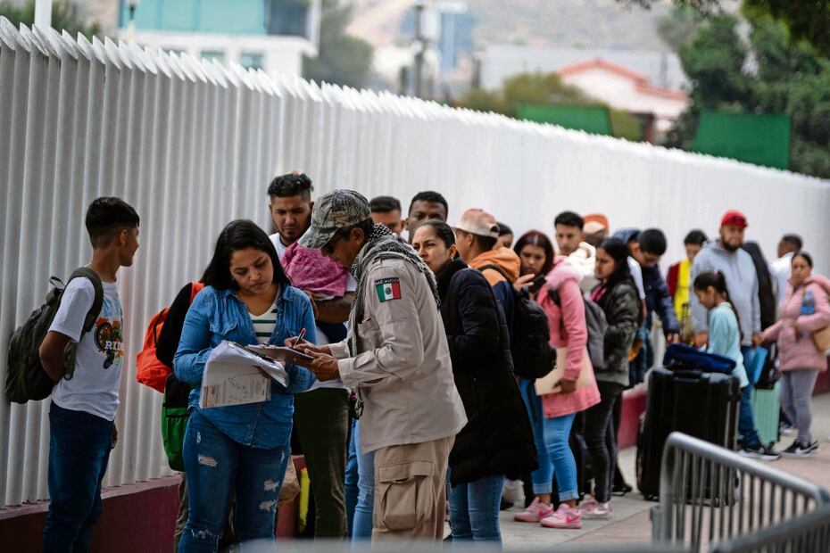Un funcionario de migración mexicano revisa los documentos de solicitantes de asilo en el puerto fronterizo de El Chaparral, antes de que asistan a su cita con las autoridades de EU. Foto: Guillermo Arias | AFP