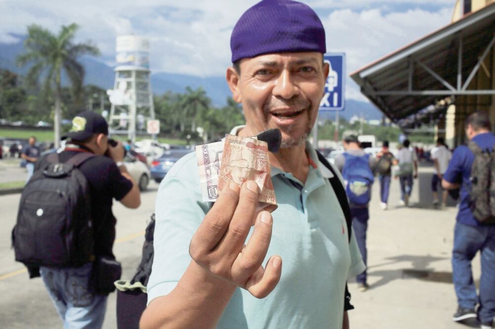 Un hombre muestra billetes de la moneda local (lempira), en la terminal de autobuses de la ciudad de San Pedro Sula, Honduras (GUSTAVO AMADOR. EFE)