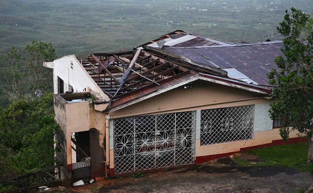 Una casa con el techo dañado se observa tras el paso del huracán Melissa en Manchester, Jamaica, el 28 de octubre de 2025. El huracán Melissa arrancó árboles y provocó cortes de luz tras tocar tierra en Jamaica el 28 de octubre de 2025, convirtiéndose en uno de los huracanes más potentes jamás registrados e inundando la isla con lluvias torrenciales que amenazaron con inundaciones repentinas y deslizamientos de tierra. Foto: AFP