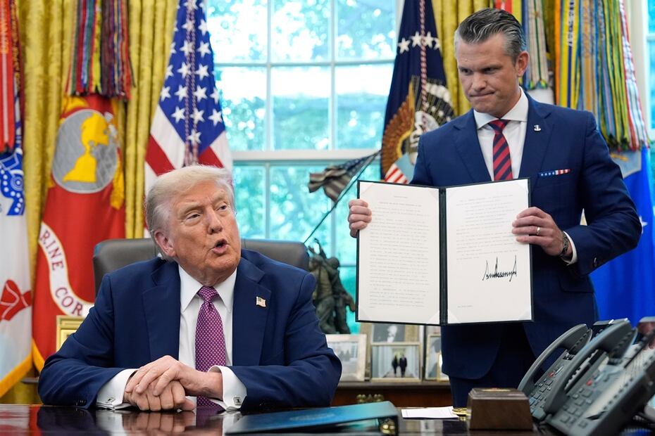 El presidente de EU, Donald Trump, habla mientras el secretario de Defensa, Pete Hegseth, sostiene una orden ejecutiva firmada en el Despacho Oval de la Casa Blanca, en Washington. Foto: AP