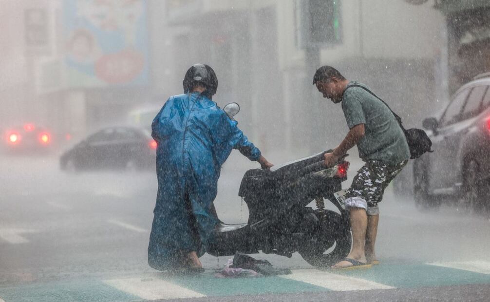 Un hombre ayuda a un automovilista con una scooter en medio de fuertes lluvias debido al supertifón Kong-rey en Keelung el 31 de octubre de 2024. Taiwán cerró el 31 de octubre cuando se acercaba el supertifón Kong-rey, lo que obligó a miles de personas a huir de una de las tormentas más poderosas que han amenazado a la isla en años. Foto: AFP