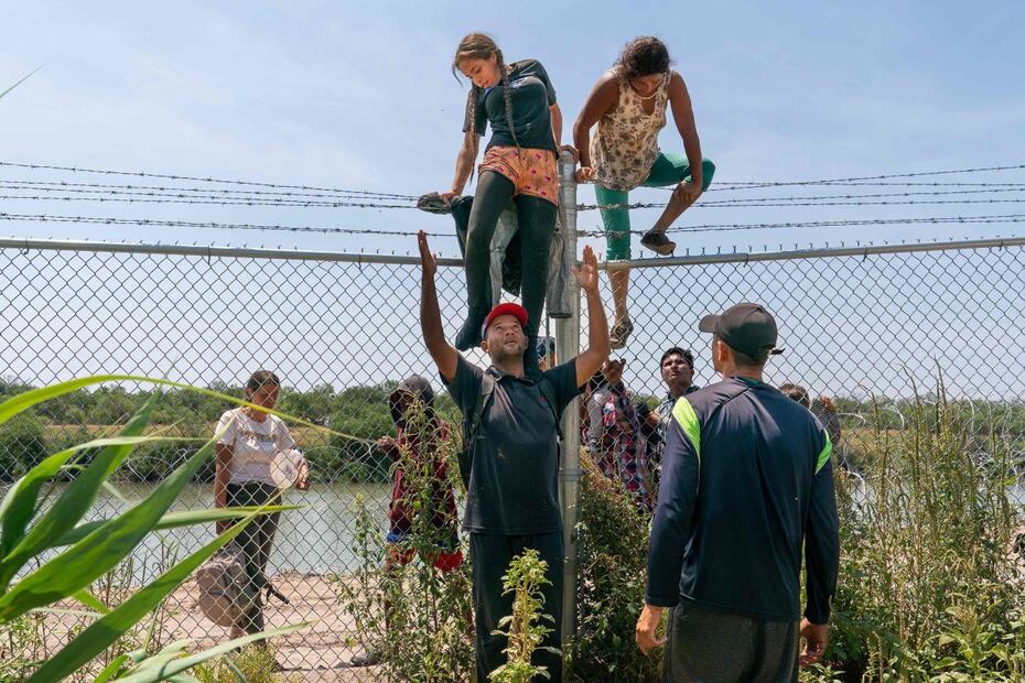 Migrantes se ayudan a trepar la cerca que separa a México de Estados Unidos, en Eagle Pass, Texas. FOTO: SUZANNE CORDEIRO. AFP