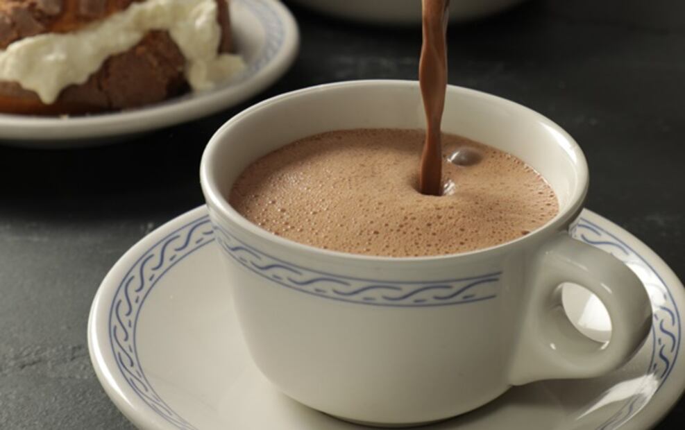 El desayuno empieza con chocolate caliente y concha con nata.