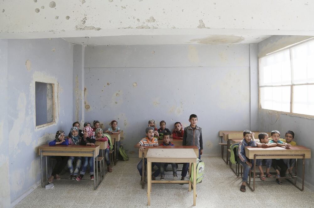 Niños sirios asisten a clases en una escuela que fue campamento militar del ejército de Bashar al-Assad, en Idlib, y hoy es área controlada por rebeldes (KHALIL ASHAWI. REUTERS)