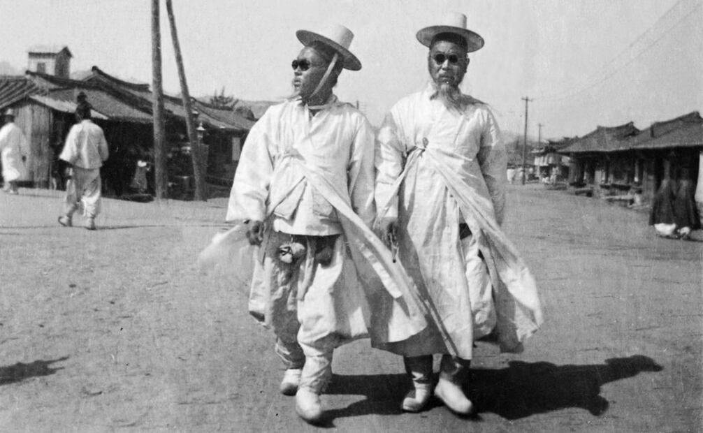 Dos hombres coreanos visten su traje tradicional en 1904, aunque su solemnidad y tradición también se acompaña con unos confiables lentes oscuros para protegerse de la luz solar. Foto: Cornell University/Wikimedia Commons.