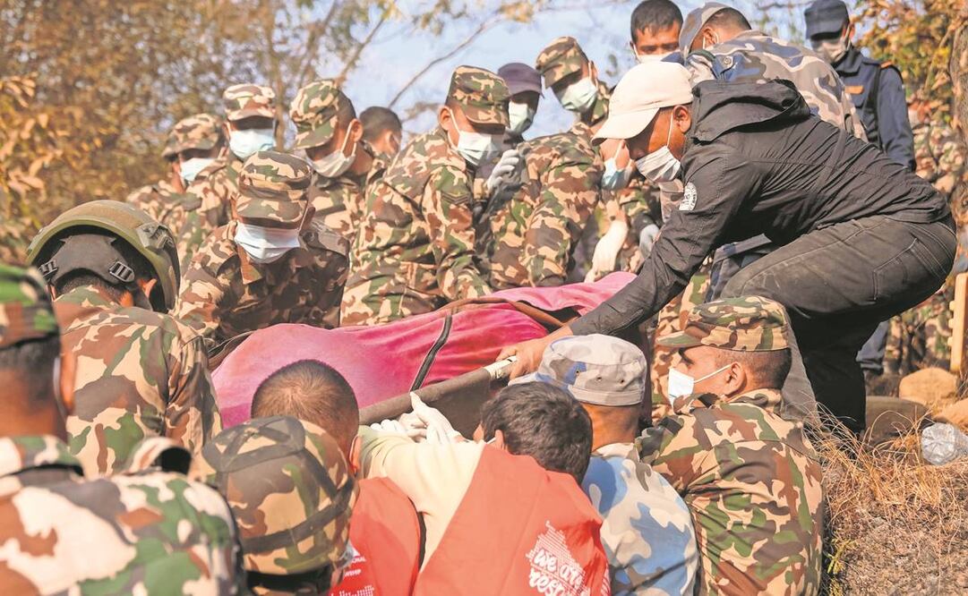Rescatistas recuperan el cadáver de una víctima del accidente de un avión en Pokhara, Nepal. El aparato quedó prácticamente carbonizado.