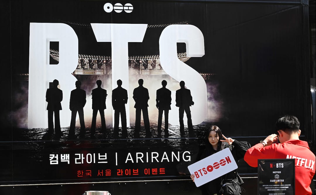 Una mujer posa para una foto frente a un camión que promociona el concierto de regreso del grupo masculino de K-pop BTS en Seúl el 19 de marzo de 2026. 
Foto de Jung Yeon-je / AFP.