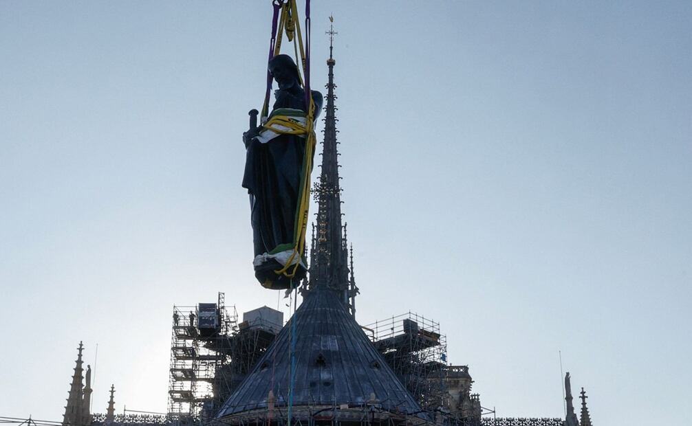 Una grúa levanta una de las estatuas gigantes de apóstoles para volver a colocarlas en la cima de la aguja de la Catedral de Notre-Dame. Foto:  AFP.