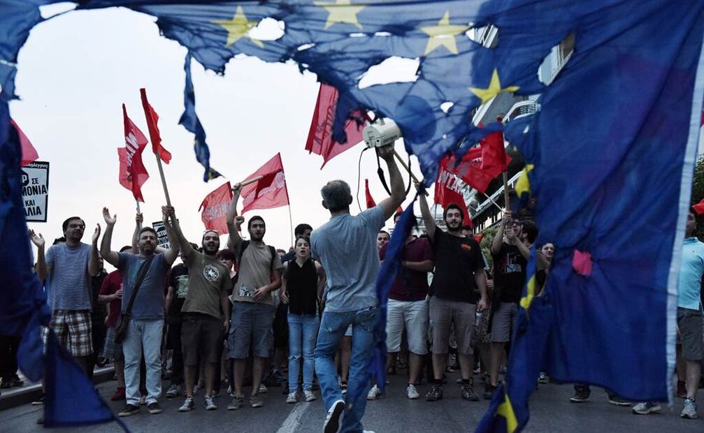 Miembros de partidos de izquierda gritan consignas mientras queman una bandera de la Unión Europea, en una protesta en el puerto de Tesalónica. (Foto: GIANNIS PAPANIKOS. AP)