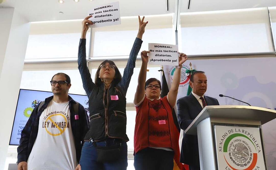 Tres personas con cartulinas exigieron cambios a la Ley Minera. Foto: Especial