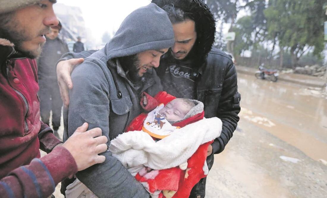 Un hombre sirio llora mientras carga a su hijo que murió en el terremoto en Jandaris.