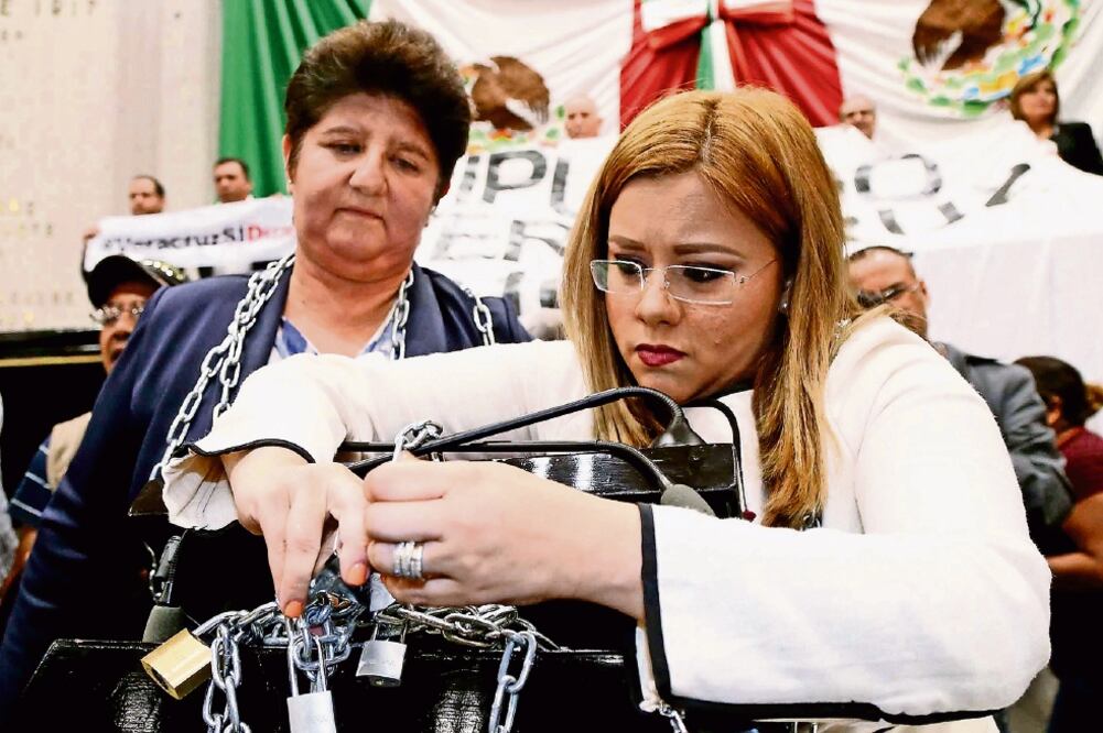 En medio de rechiflas y mantas a favor y en contra de la reforma, las diputadas locales panistas María del Carmen Ponton y Ana Ledesma se encadenaron a la tribuna para evitar la aprobación del dictamen (PATRICIA MORALES. EL UNIVERSAL)