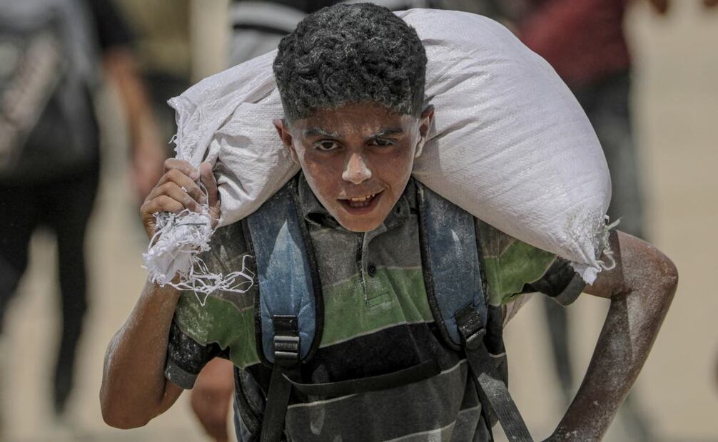 Un joven palestino lleva una bolsa de harina cerca de un punto de distribución de alimentos en Zikim este viernes, en el norte de la Franja de Gaza. Las organizaciones humanitarias han advertido de una catástrofe alimentaria inminente para miles de niños, una crisis provocada por la grave inseguridad alimentaria, el deterioro de los servicios sanitarios y las continuas restricciones a la ayuda humanitaria y los suministros esenciales. Foto: EFE