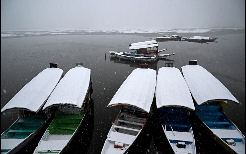Imagen de barcos cubiertos de nieve cerca de una parte congelada del lago Dal durante una nevada en Srinagar. Foto: AFP