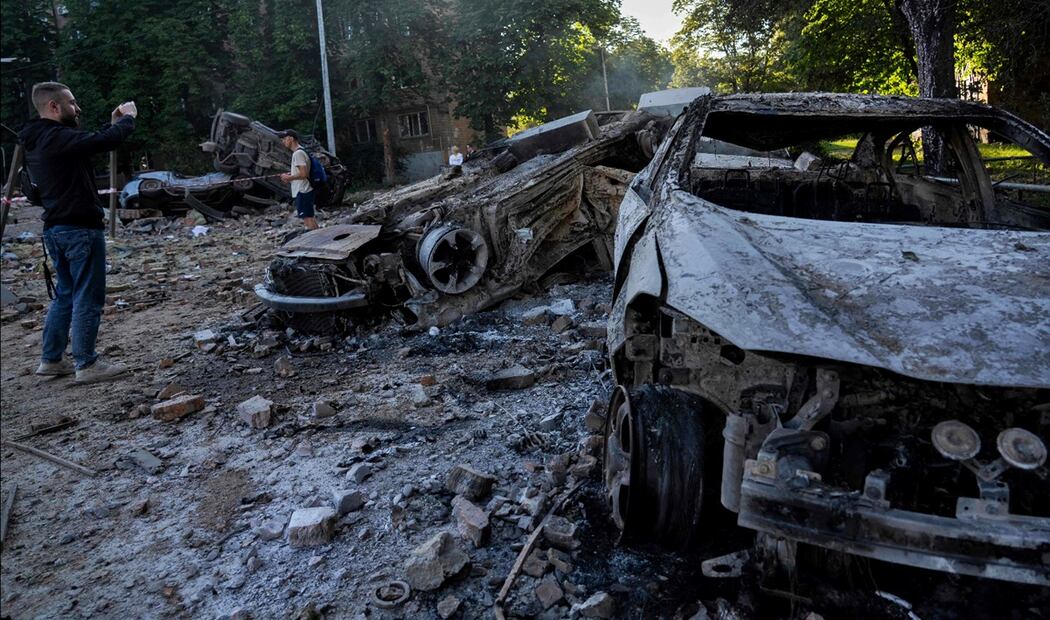 Hombres observan y toman fotos de vehículos destruidos tras los masivos ataques con drones y misiles rusos contra Kiev, Ucrania, el 4 de julio de 2025. Foto: AFP