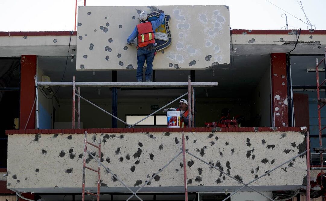 Trabajadores reparando la fachada del ayuntamiento, lleno de agujeros de bala, en Villa Unión, México. (AP Foto/Eduardo Verdugo)