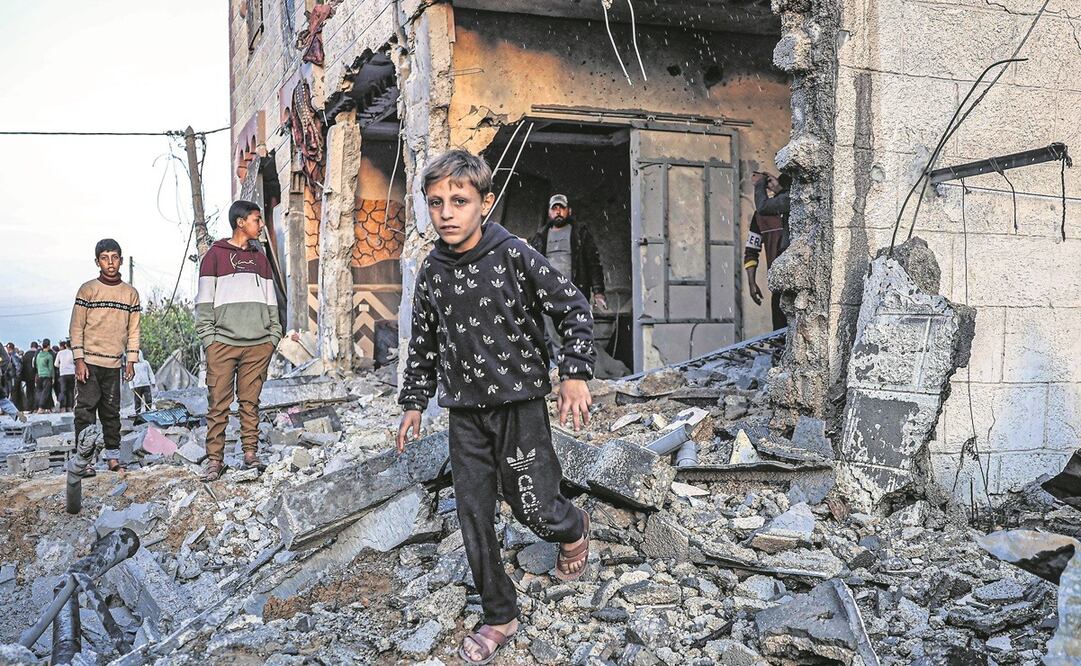 Palestinos caminan entre los escombros de un edificio dañado por bombardeos israelíes, en Rafah, en el sur de la Franja de Gaza. Foto: AFP