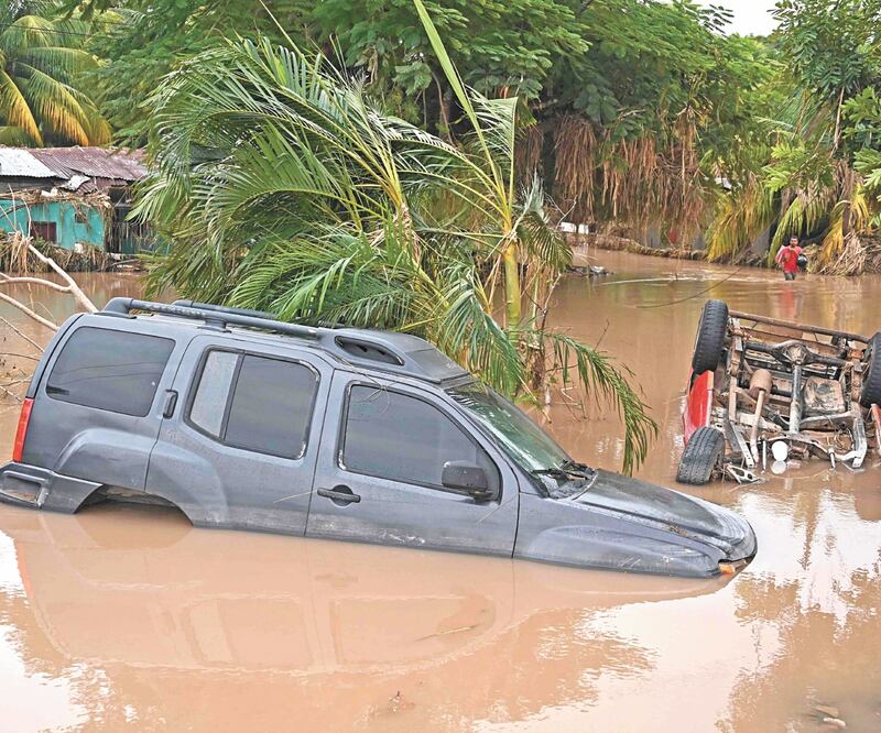 Vehículos seguían sumergidos en el agua ayer en La Lima, en Honduras, tras el paso del huracán Eta. ORLANDO SIERRA. AFP