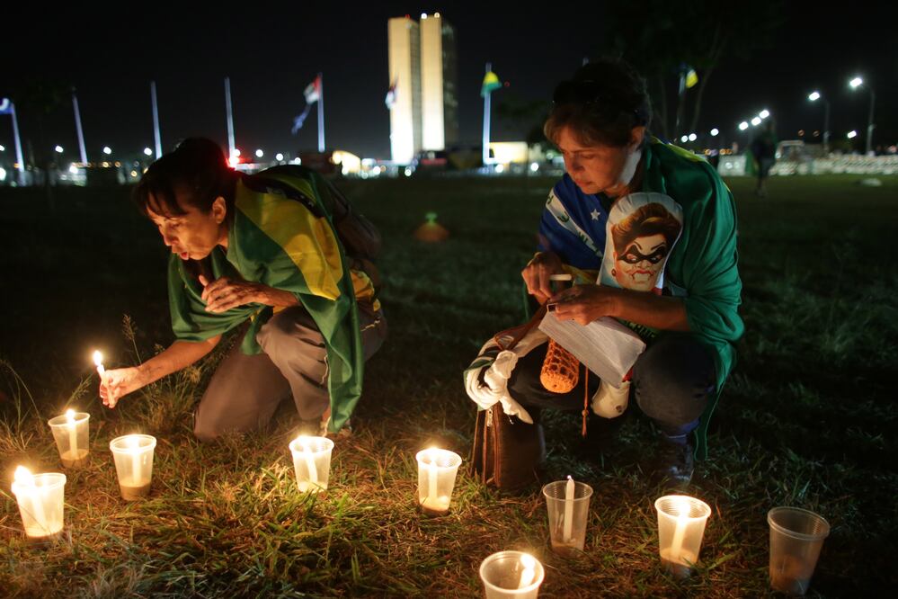 Manifestantes contrarios al gobierno encienden velas ante el Congreso brasileño, donde los legisladores debaten si impugnar a la presidenta Dilma Rousseff. (AP)