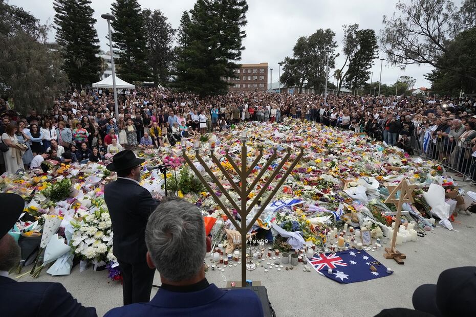 El rabino Motti Feldman, abajo a la izquierda, habla en una ceremonia de encendido de la menorá en un homenaje floral a las víctimas del tiroteo del domingo, en la playa Bondi, en Sidney, Australia. FOTO: MARK BAKER. AP