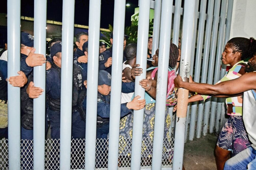 Migrantes africanos jalonean la valla del Instituto Nacional de Migración mientras policías federales tratan de bloquearles el paso a las instalaciones. Foto: JOSÉ TORRES. REUTERS