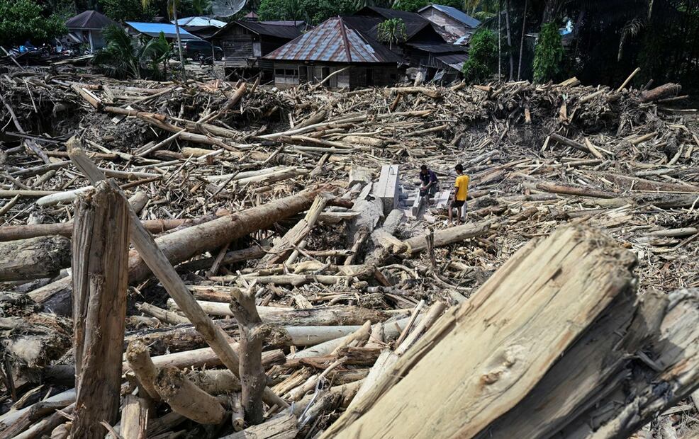 Entre miles de escombros, aldeanos cortan troncos arrastrados por las inundaciones con la intención de usarlos como material para reconstruir sus hogares dañados en Garoga, provincia de Sumatra del Norte, el 4 de diciembre de 2025. Foto: AFP