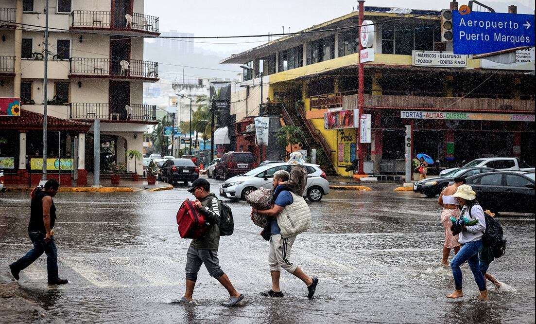 Personas caminan por una calle encharcada debido a las fuertes lluvias provocadas por el huracán Hilary en Acapulco, Guerrero. Foto: EFE